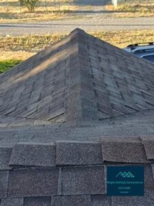 Close-up of a newly installed hip roof with gray asphalt shingles, featuring a Wright's Roofing & Construction Inc. logo watermark in the corner.